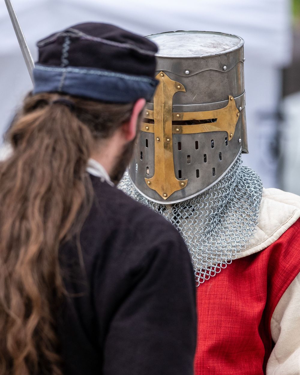 Chevalier en armure échangeant avec un participant lors d'un spectacle médiéval.