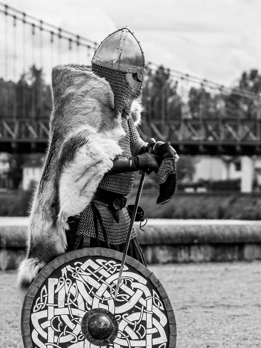 Guerrier en costume médiéval tenant un bouclier lors d'une reconstitution historique.