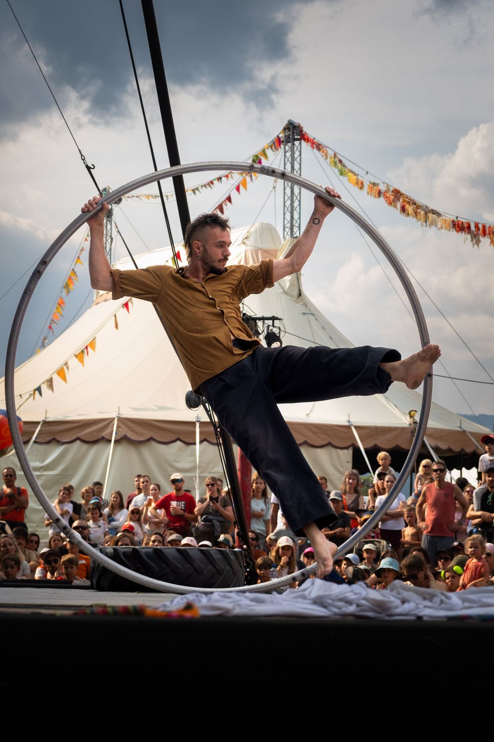 Artiste de cirque évoluant dans un cerceau aérien lors d'un spectacle en plein air.