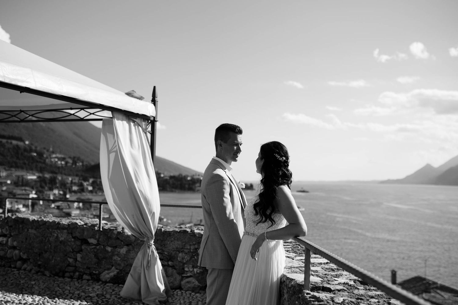 Couple sharing a romantic moment at an outdoor wedding ceremony overlooking a scenic coastal landscape in black and white.