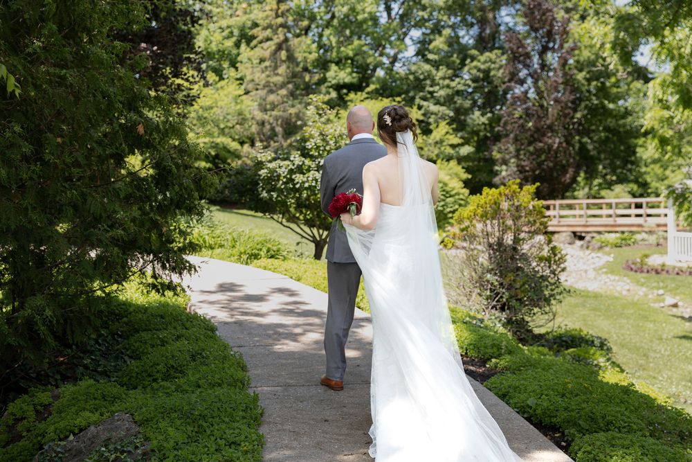 Bride walks to her dad during first look along a garden path at the civic garden complex in london, ontario.