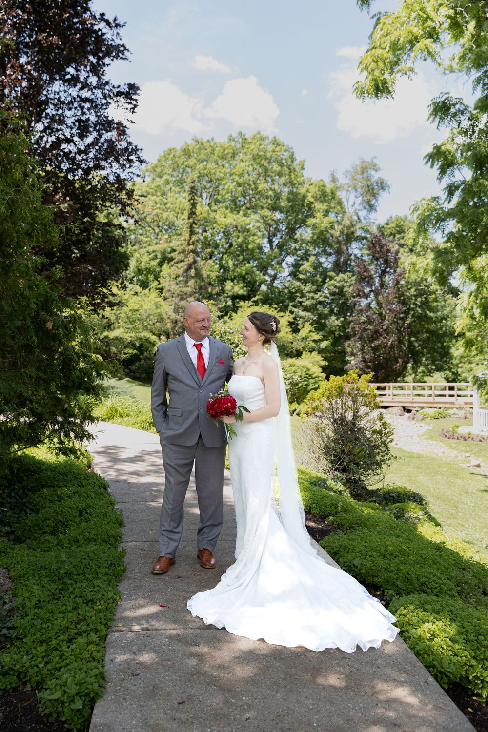 Bride and father stand on a path surrounded by greenery at the civic garden complex in london, ontario wedding.