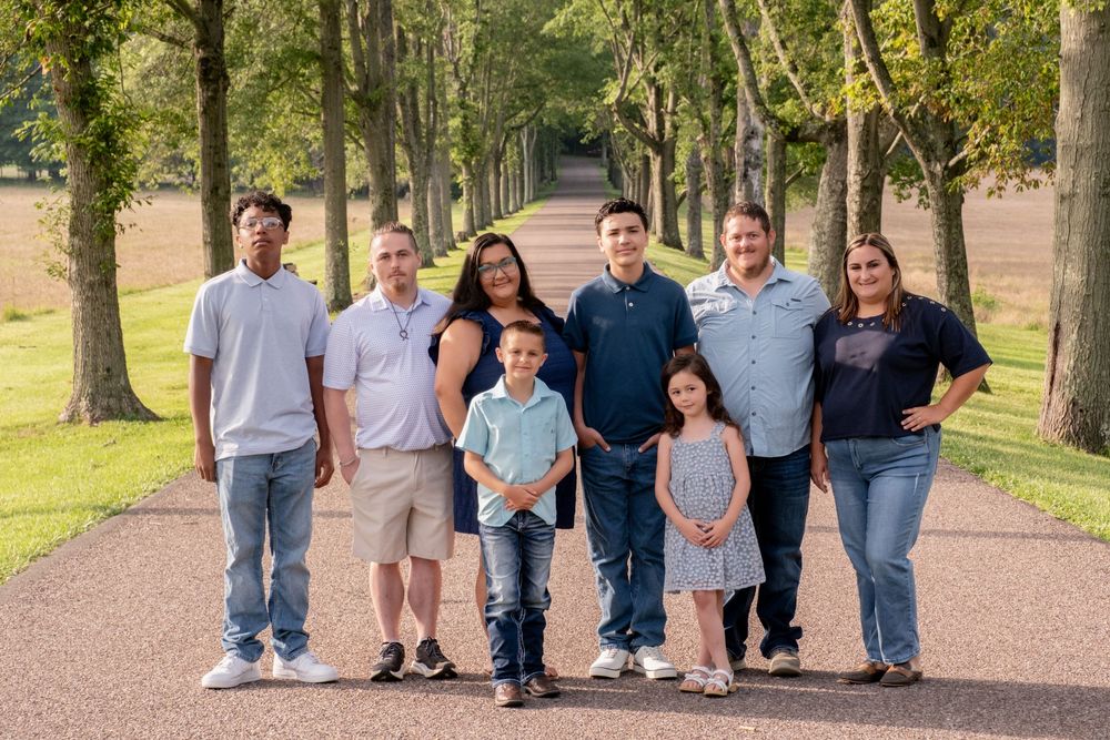 Family of eight posing on a tree-lined path in a park during a warm sunny day. Uniontown, PA