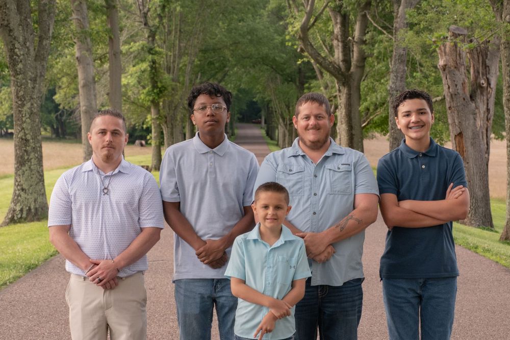 Five males of varying ages pose together on a tree-lined path in an outdoor family portrait. Uniontown, PA