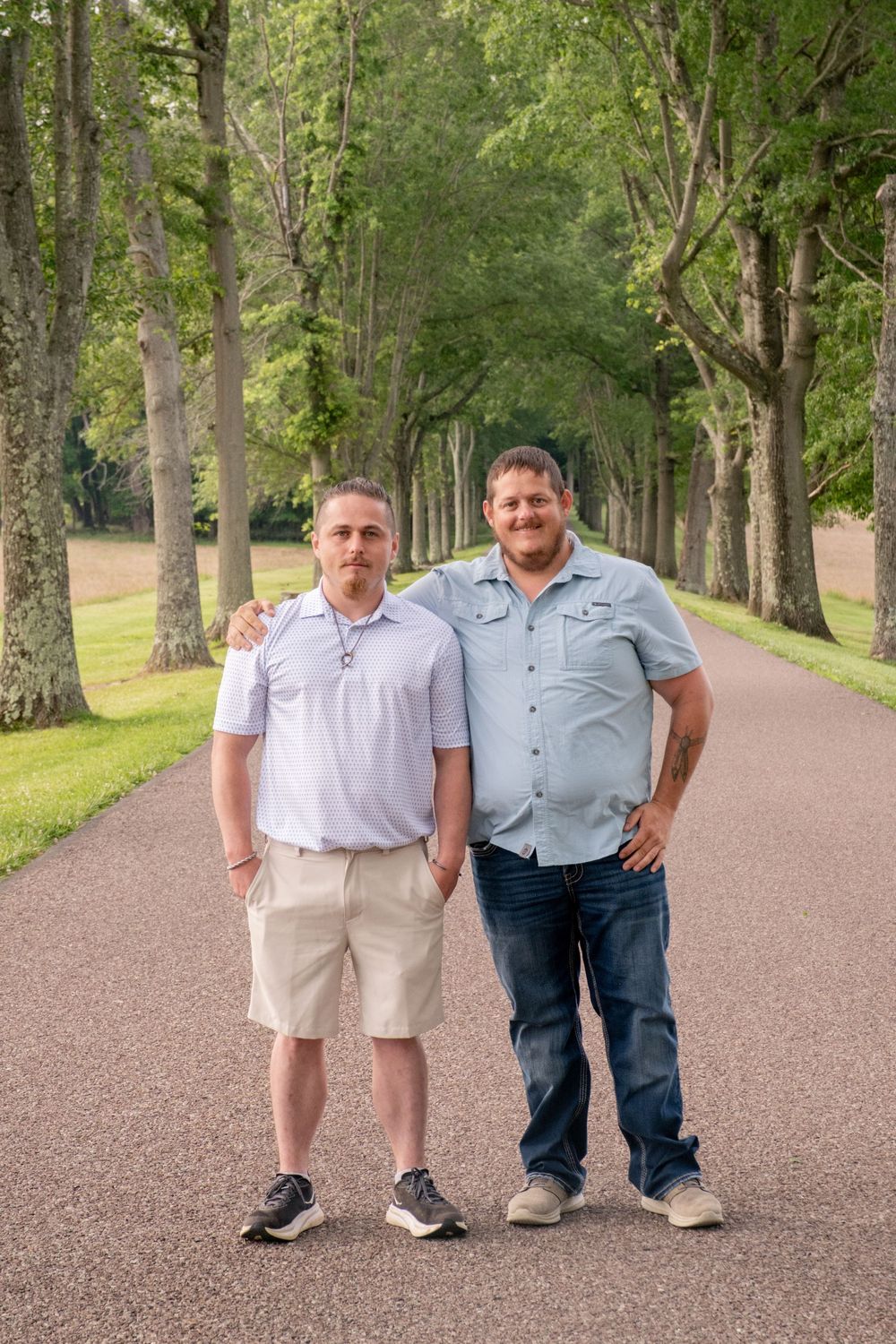 Two men smiling and posing together on a tree-lined path outdoors on a sunny day. Uniontown, PA