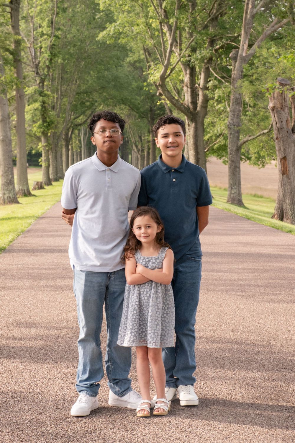 Two teenage boys and a young girl pose on a tree-lined path in a park for a family portrait. Uniontown, PA
