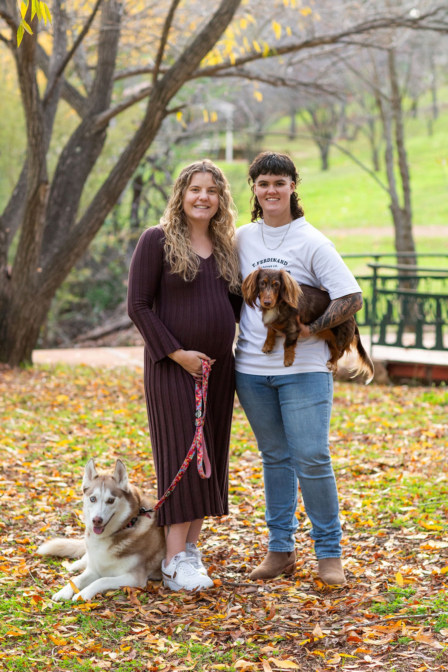 Couple embracing their husky and dachshund during pet photography session in perth