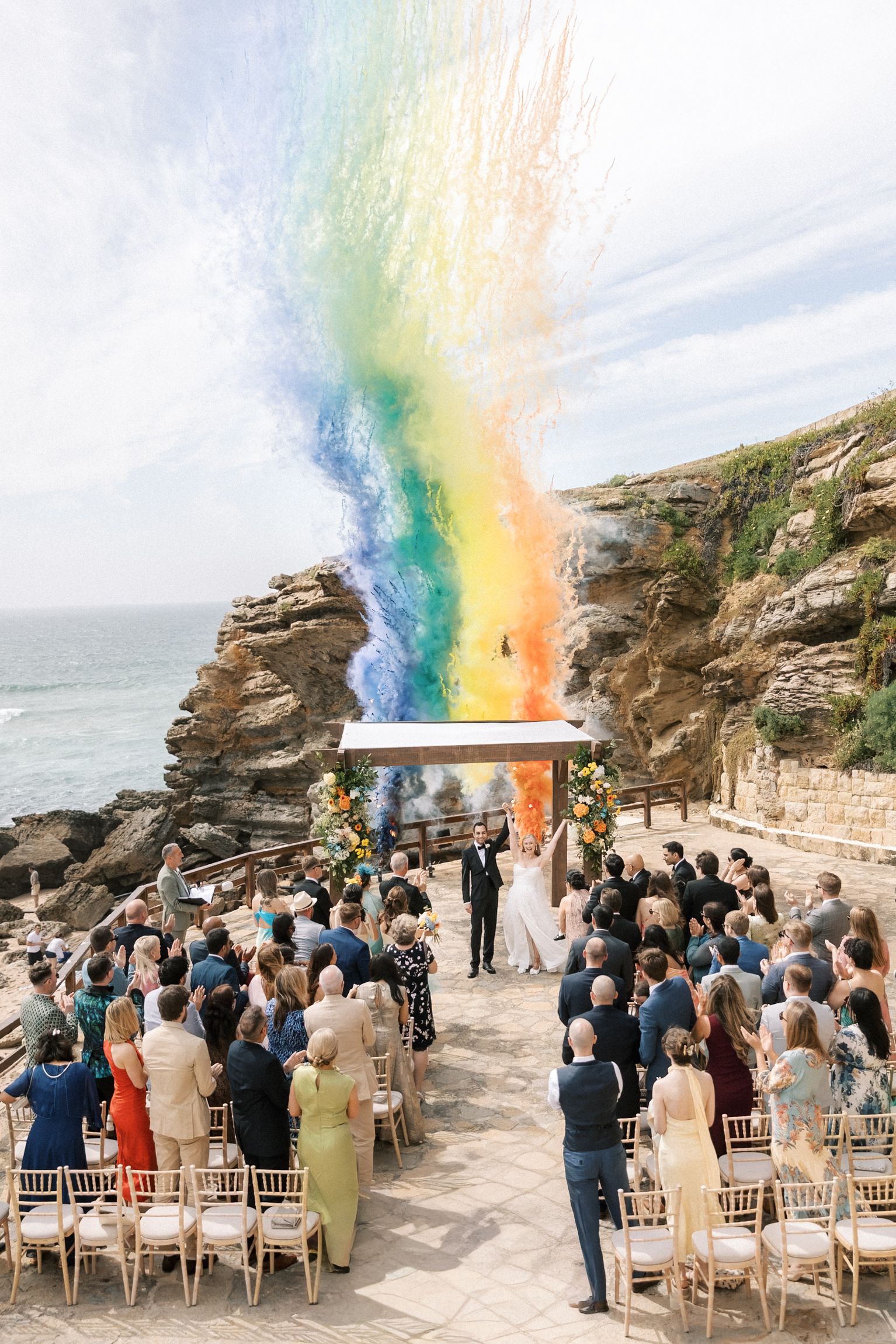 Newlyweds celebrating with colourful smoke after their wedding ceremony overlooking the Atlantic Ocean at Arriba by the Sea.