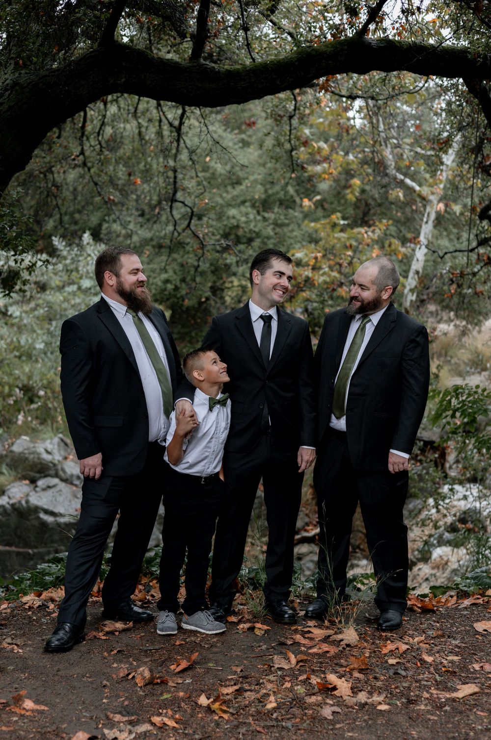 Groom, groomsmen and ringbearer pose for a happy picture together.