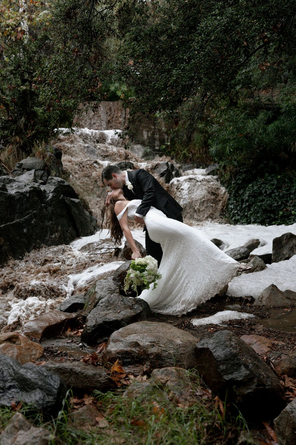 Groom dips bride back for waterfall wedding pictures.