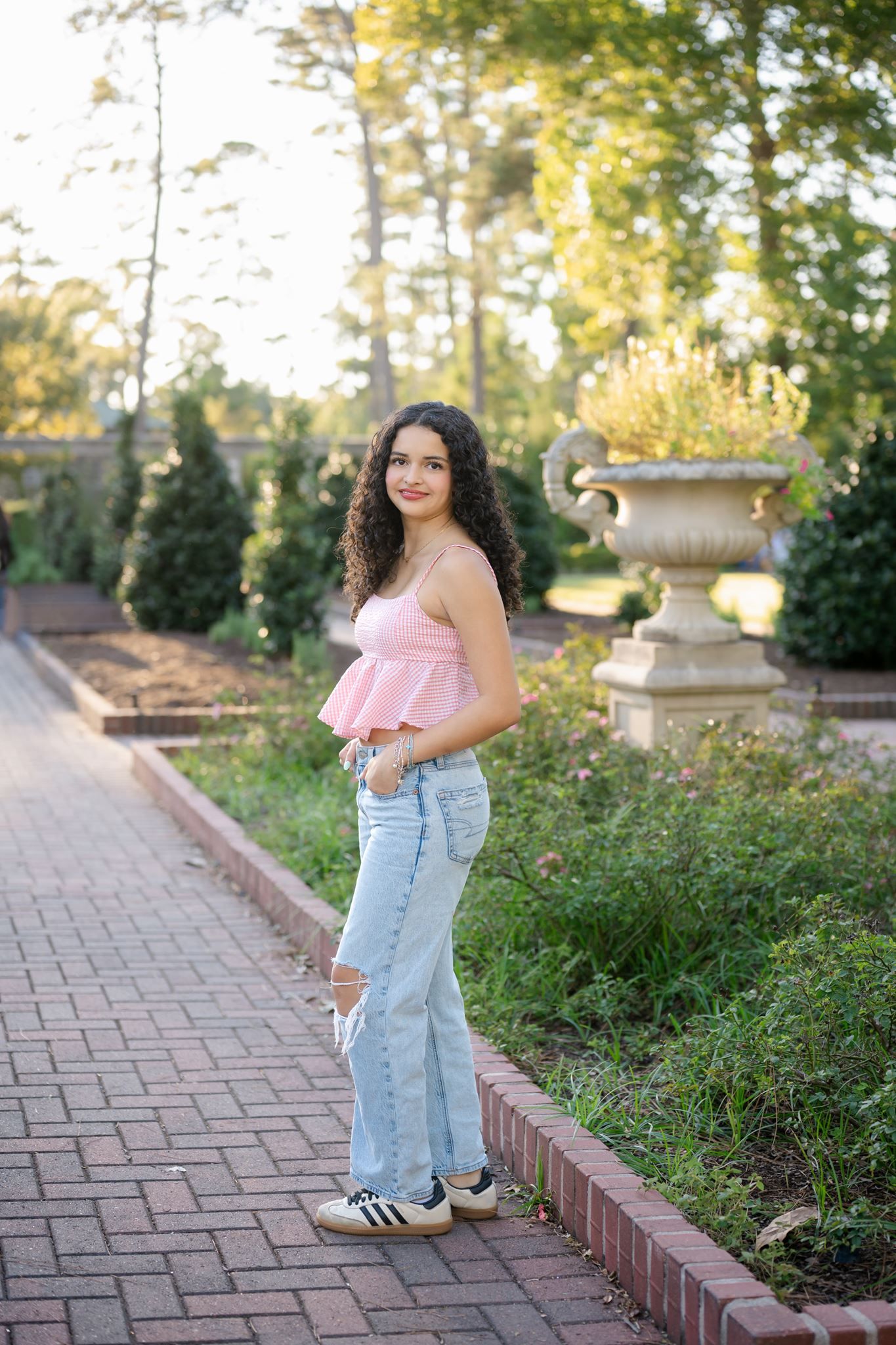 Casual senior girl portrait featuring a pink peplum top and natural garden background.