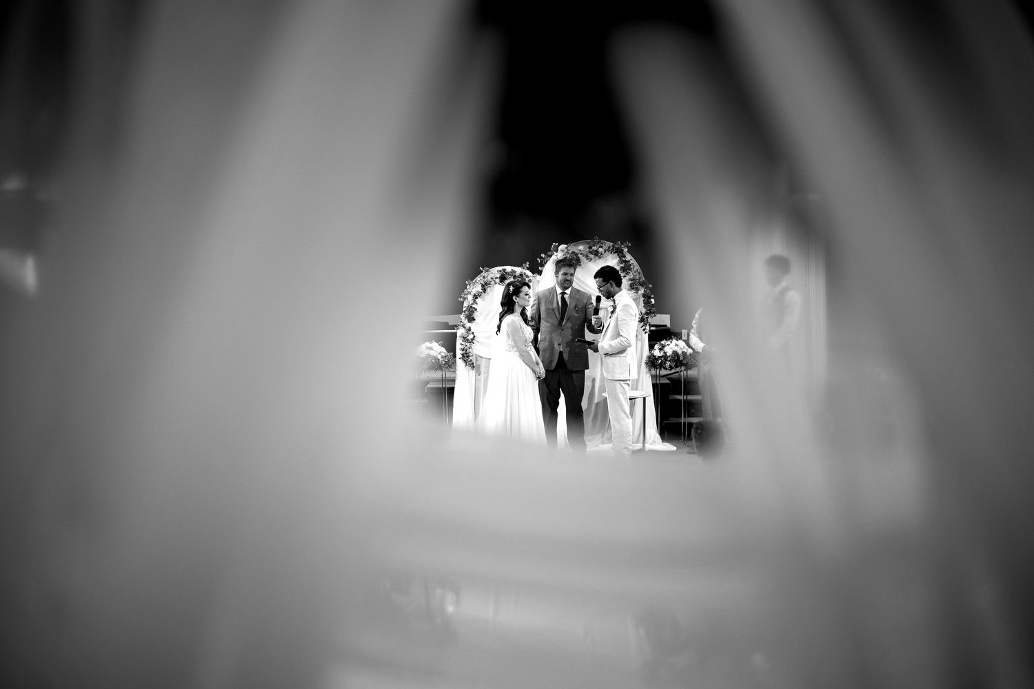 Black and white view of the couple at the altar framed through a soft blurred foreground at King's Gate Church