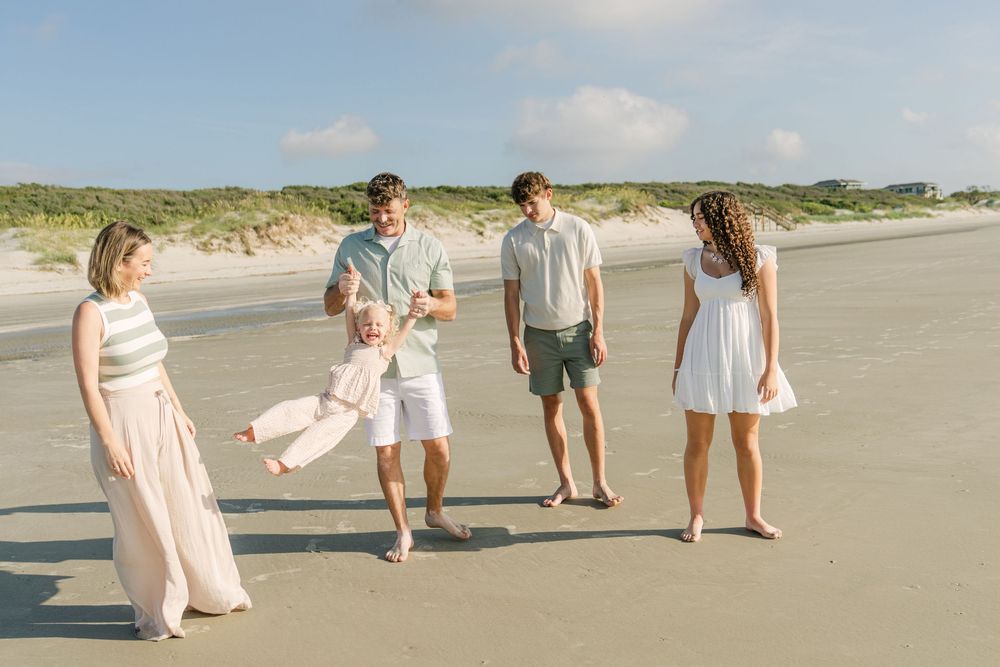 Family smiling together with the ocean behind them on near Fernandina Beach and Amelia Island and Golden Isles
