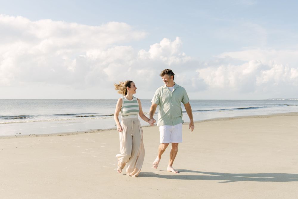 Parents walking together beside the ocean during their Golden Isles beach portrait session.