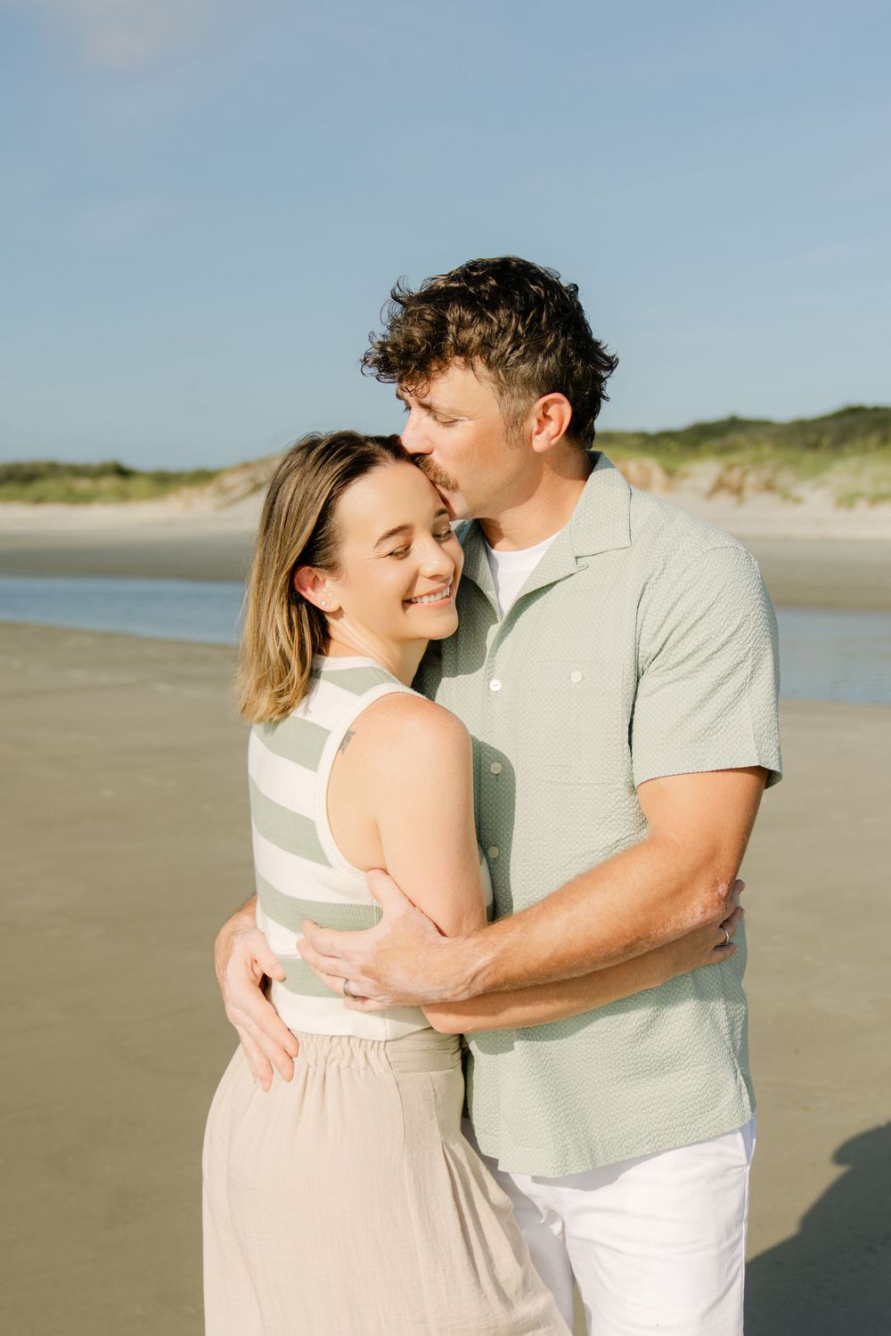 Parents cuddling during a family beach session on Jekyll Island, Georgia on a summer mid-morning photography session.