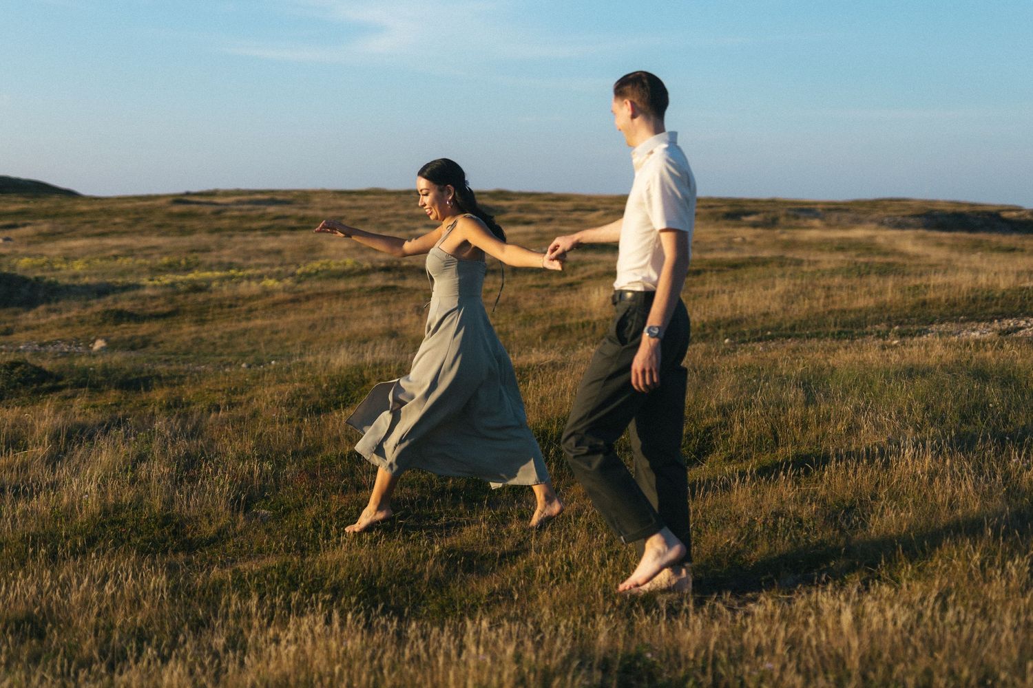 barefoot bride and groom run through a meadow of tall grass during Vancouver Island elopement