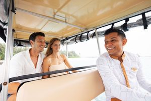 Three smiling people relaxing on a boat, two tourists and a local guide enjoying a sunny day on the water.