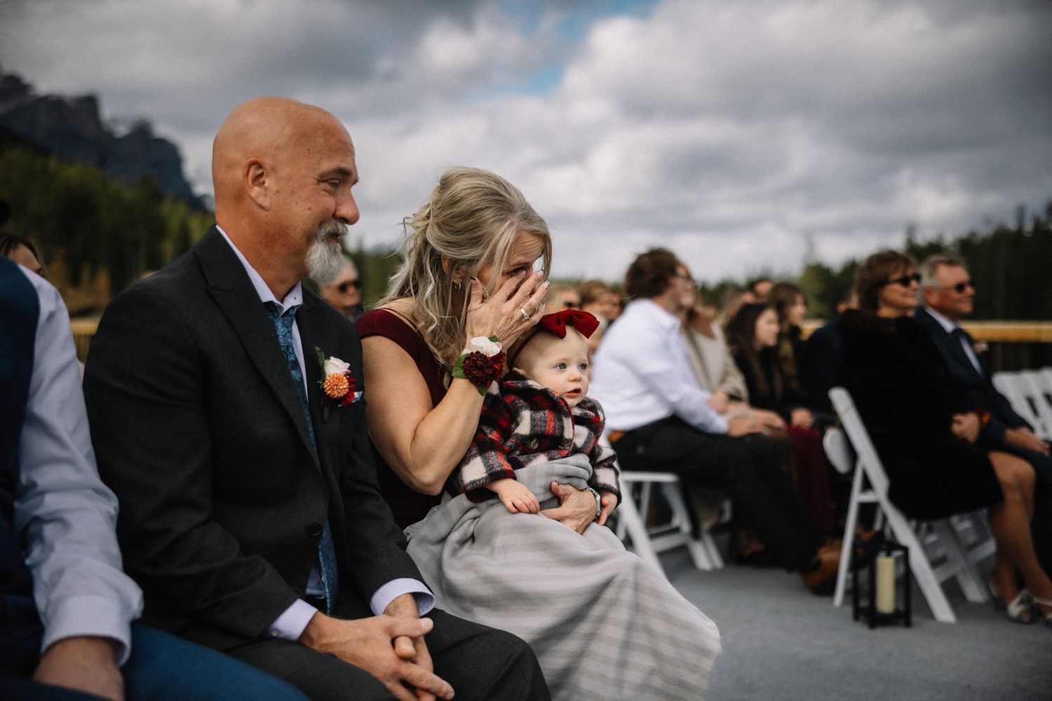 Emotional guests wiping happy tears during an outdoor mountain wedding ceremony