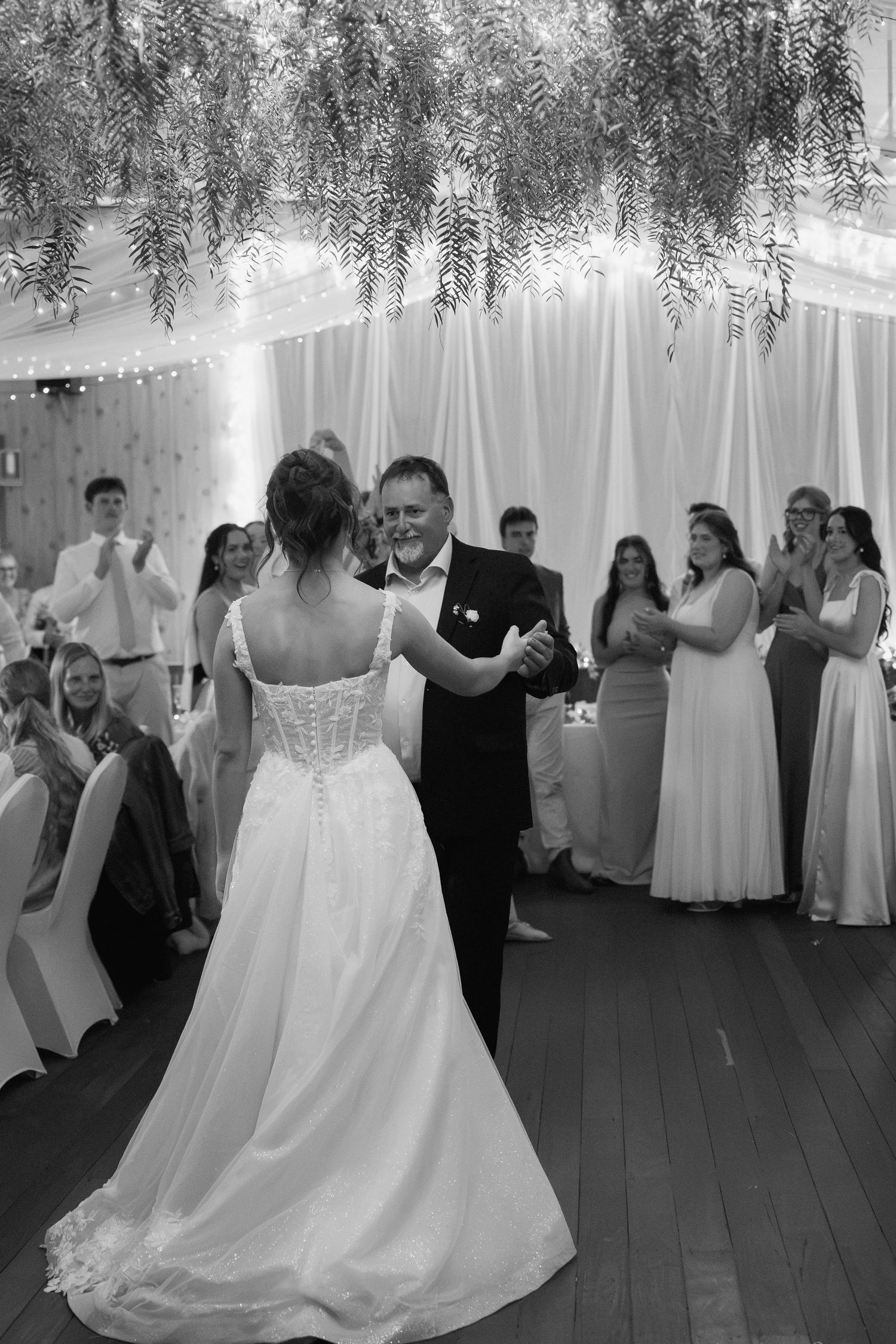 Bride dancing with father during first dance at wedding reception in black and white photo.