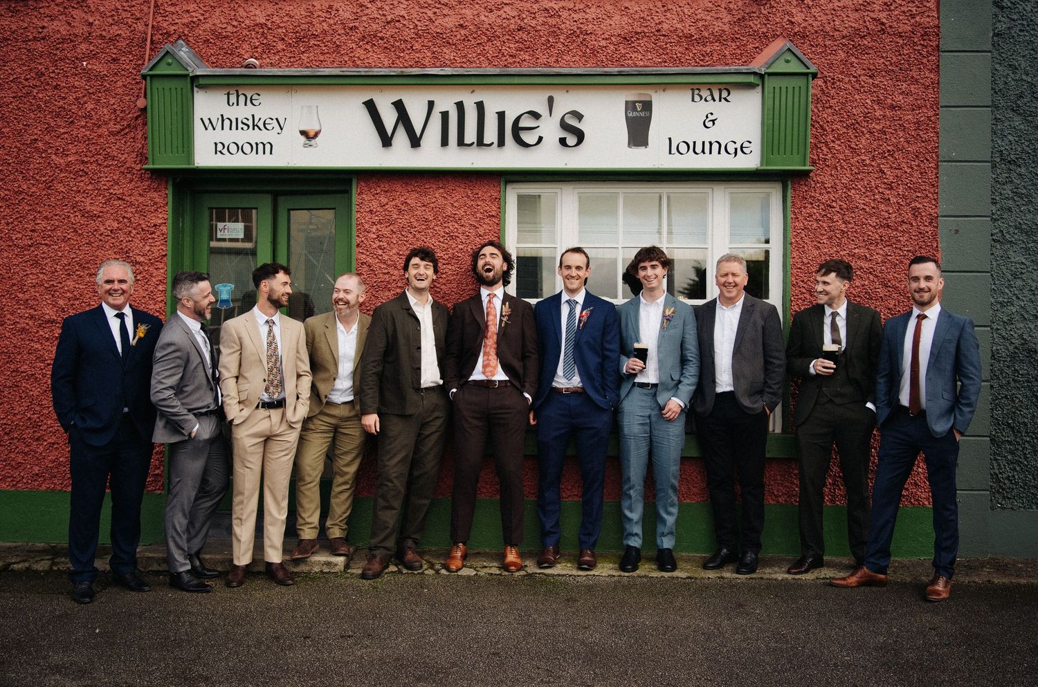 Group of men in suits posing outside Willie's Bar & Lounge whiskey room in Ireland.