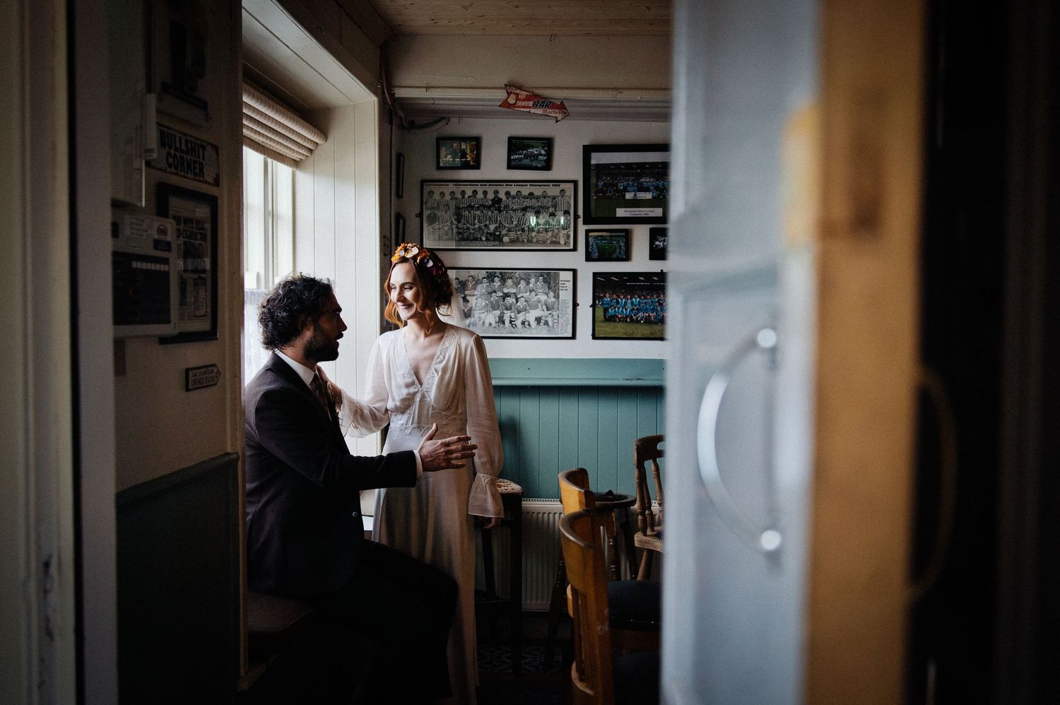 Couple sharing an intimate moment in a cozy room with framed photos on the wall.