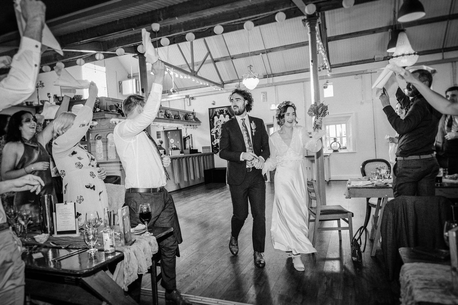 Black and white photo of a bride and groom making a grand entrance at their wedding reception.