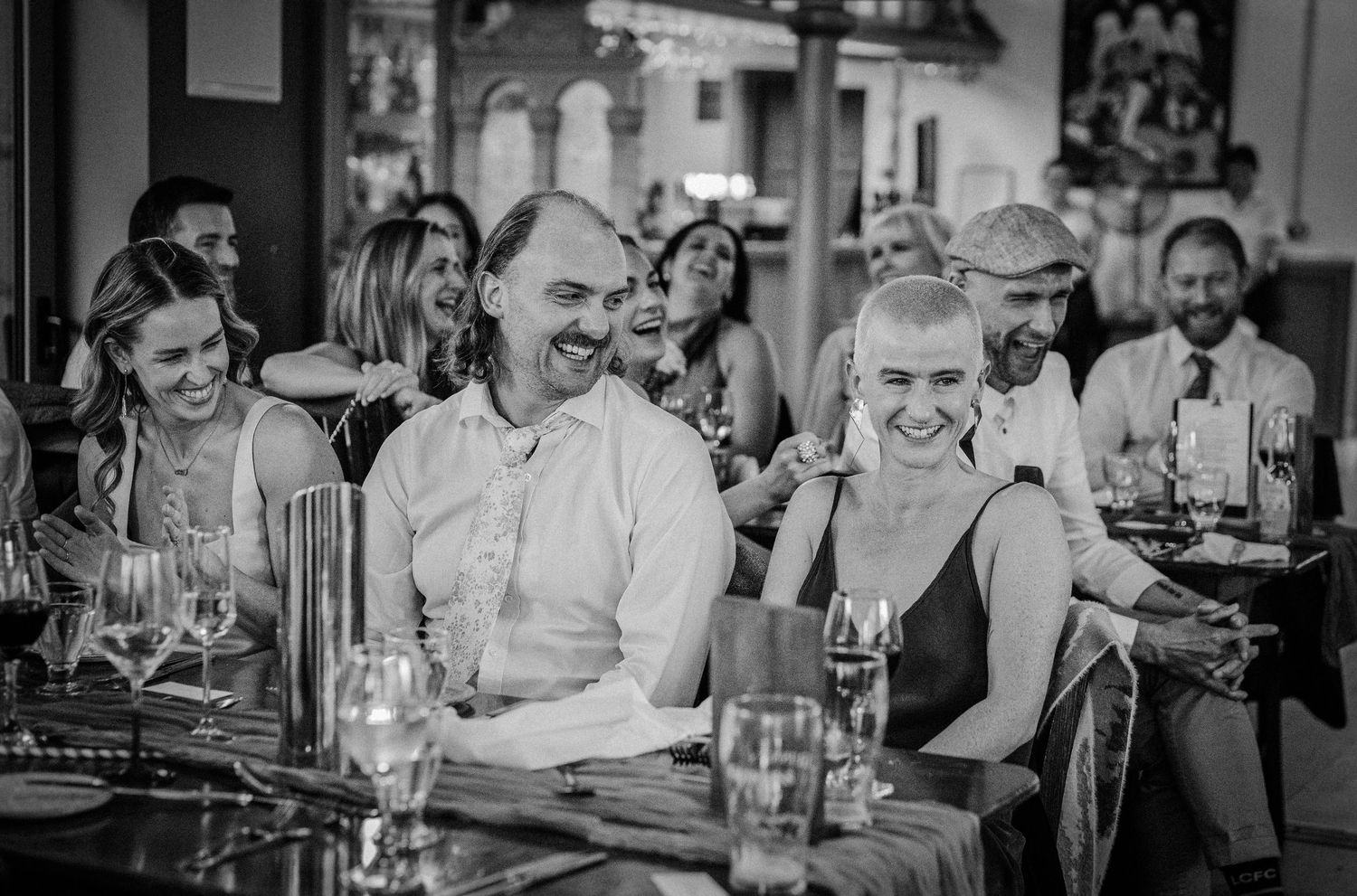 Black and white photo of smiling guests laughing at a restaurant dinner party event.