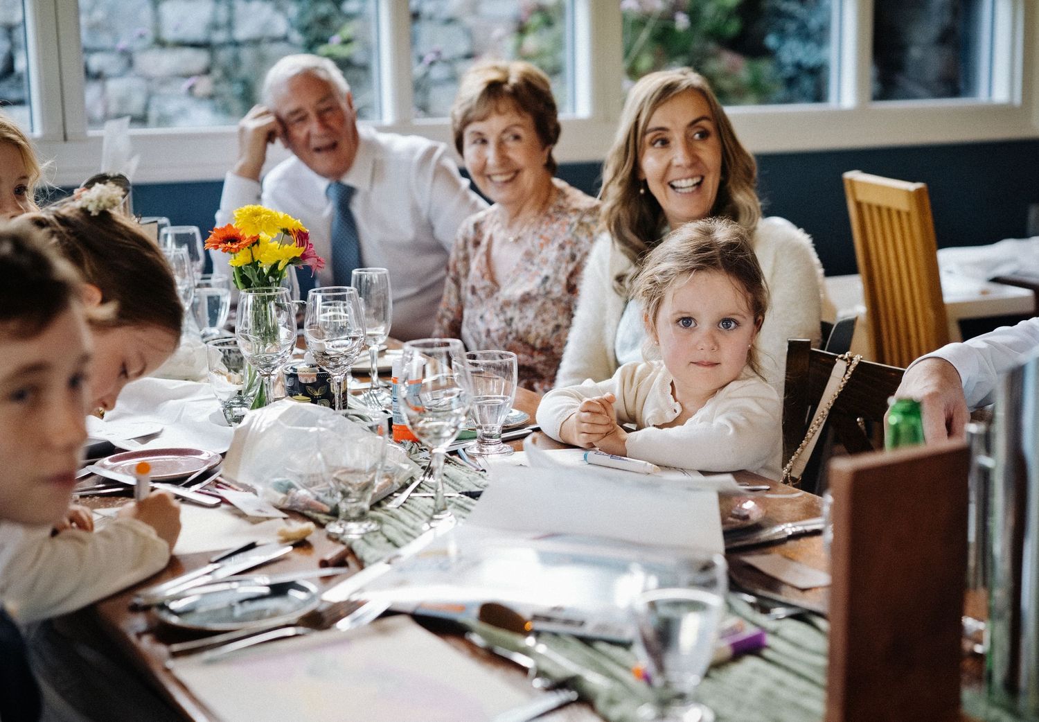 Multi-generational family gathered around a festive dining table, smiling and enjoying a celebration meal together.