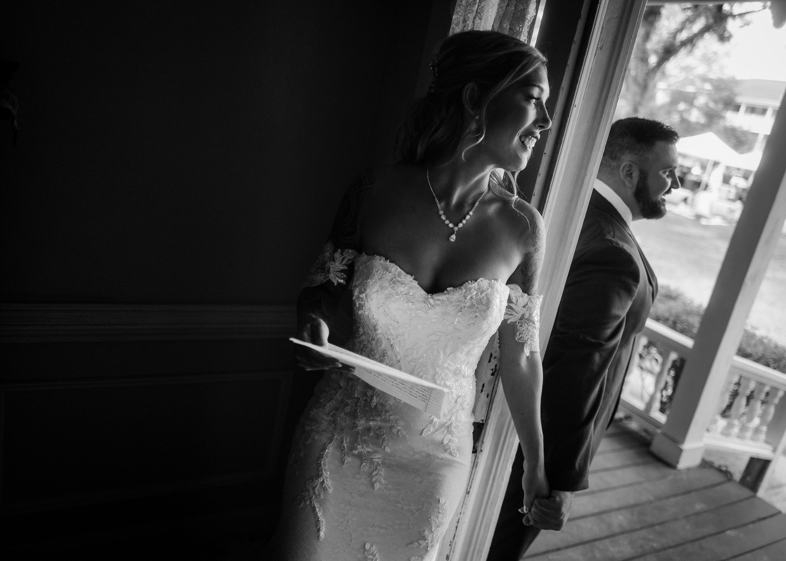 A bride and groom share a romantic kiss under a white veil on their wedding day outdoors.