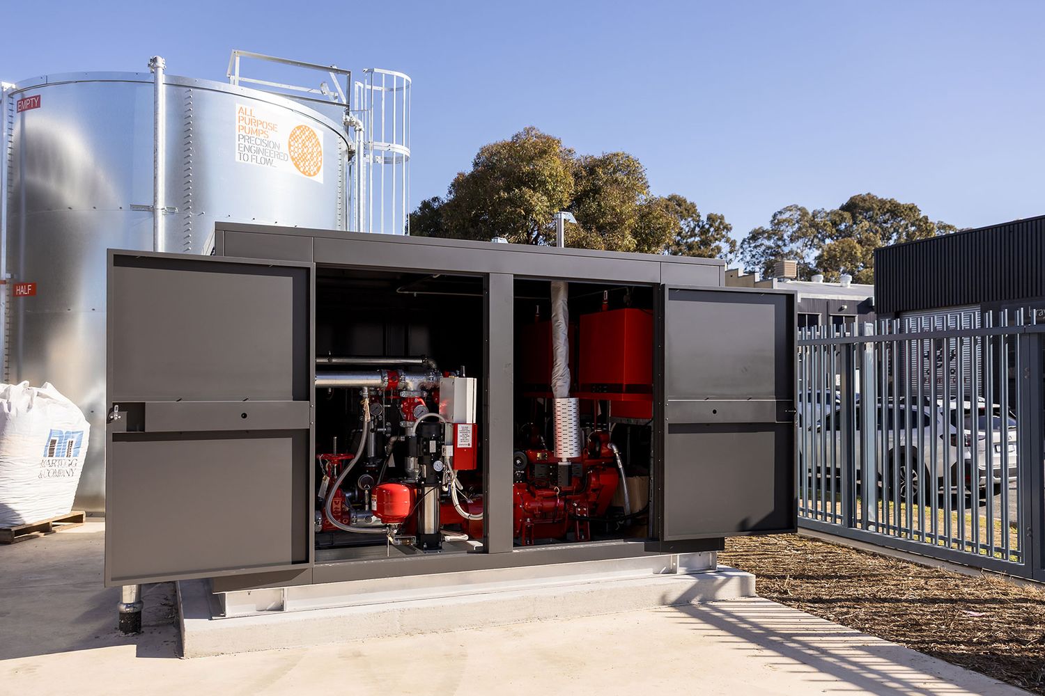 Industrial pump system housed in a gray metal cabinet enclosure, installed outdoors at an Australian facility.