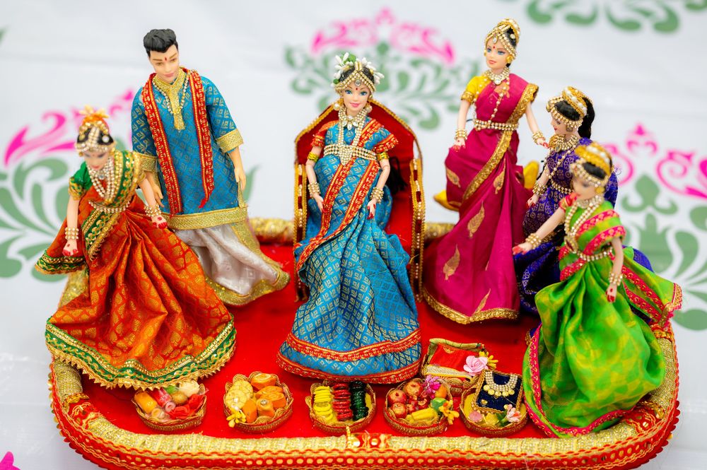 Colorful traditional Indian wedding dolls displayed on a red tray, depicting a bridal ceremony with ornate costumes.