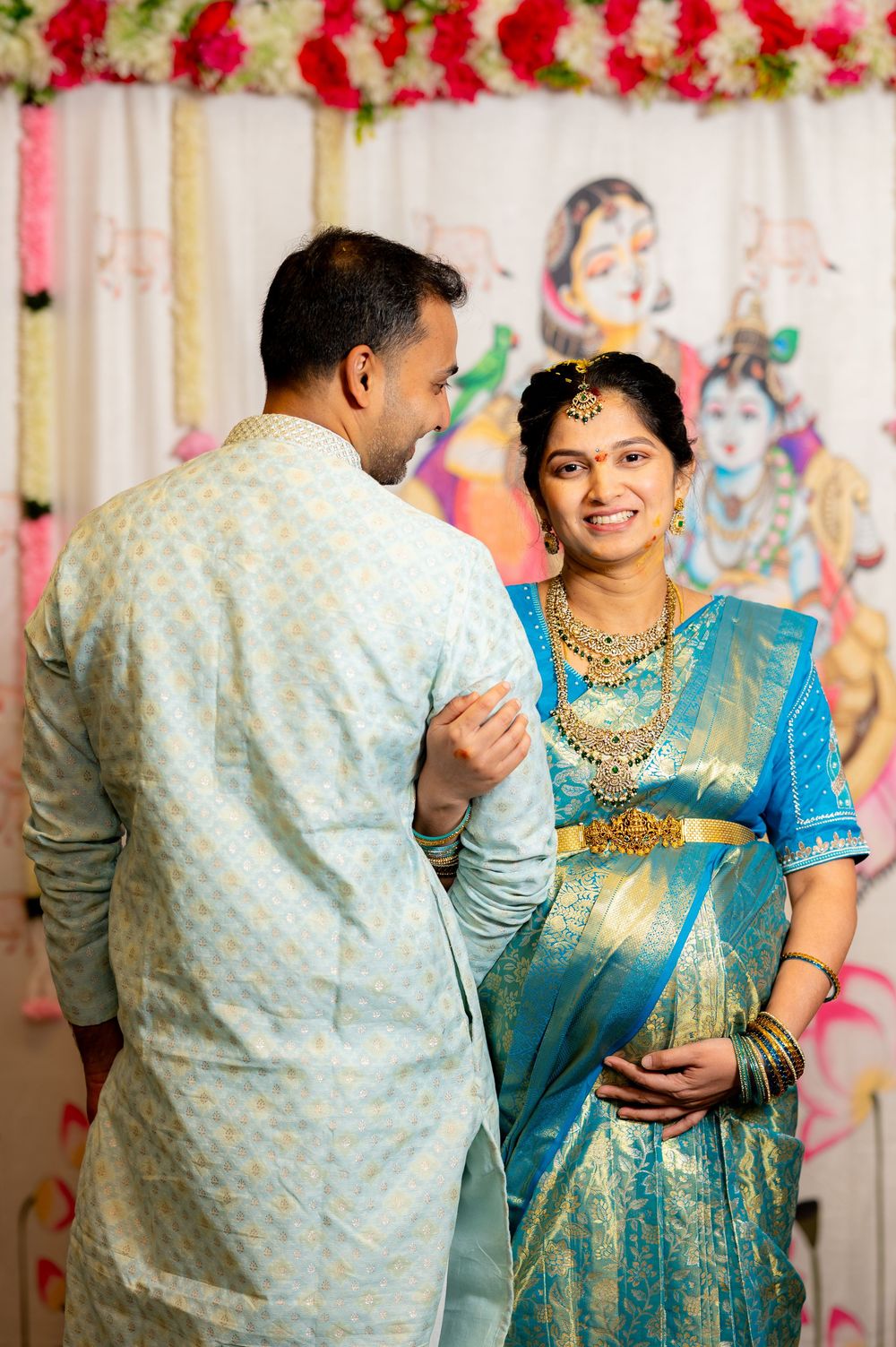 Indian couple in traditional attire, bride in blue Kanjivaram saree with gold jewelry, groom in light kurta, Hindu wedding ceremony.