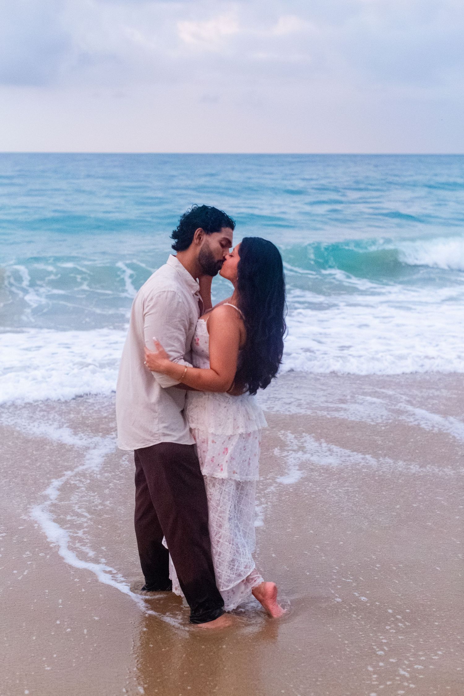 Engagement portrait on the beach. Man and woman kissing at the water's edge. Playa Guajataca, Isabela, Puerto Rico.
