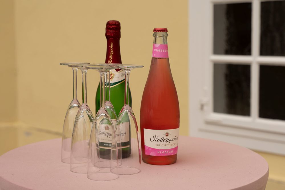 Two bottles of champagne and sparkling rose with elegant glasses on a pink table at a wedding reception.