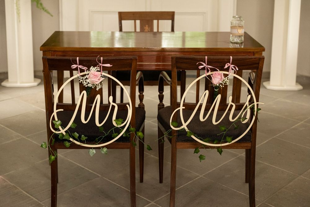 Wooden Mr and Mrs wedding chair signs decorated with floral hoops at a reception table.