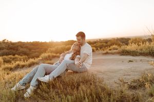 Couple embracing at golden hour sunset in a dry grassy field, romantic outdoor engagement photo.