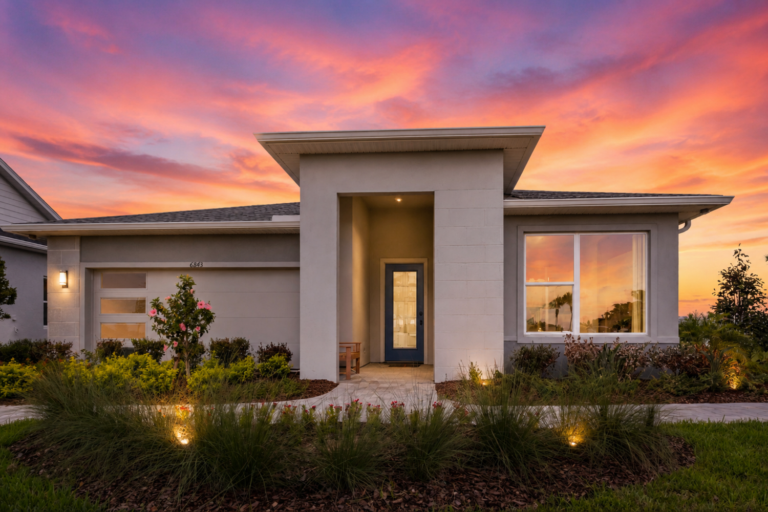Luxury backyard pool with spa at sunset, featuring a stunning orange and pink sky behind a modern home.