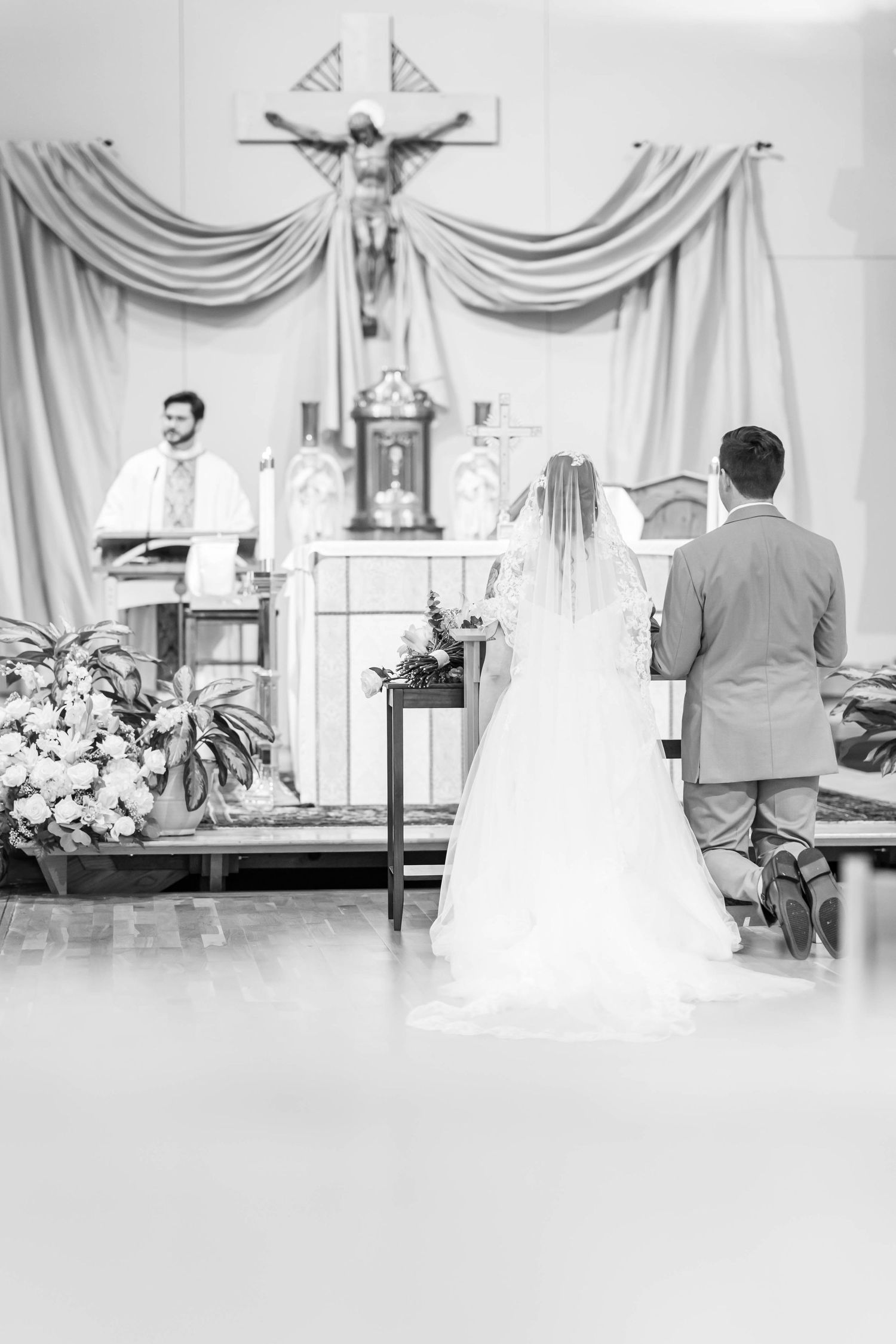bride and groom kneel during catholic ceremony
