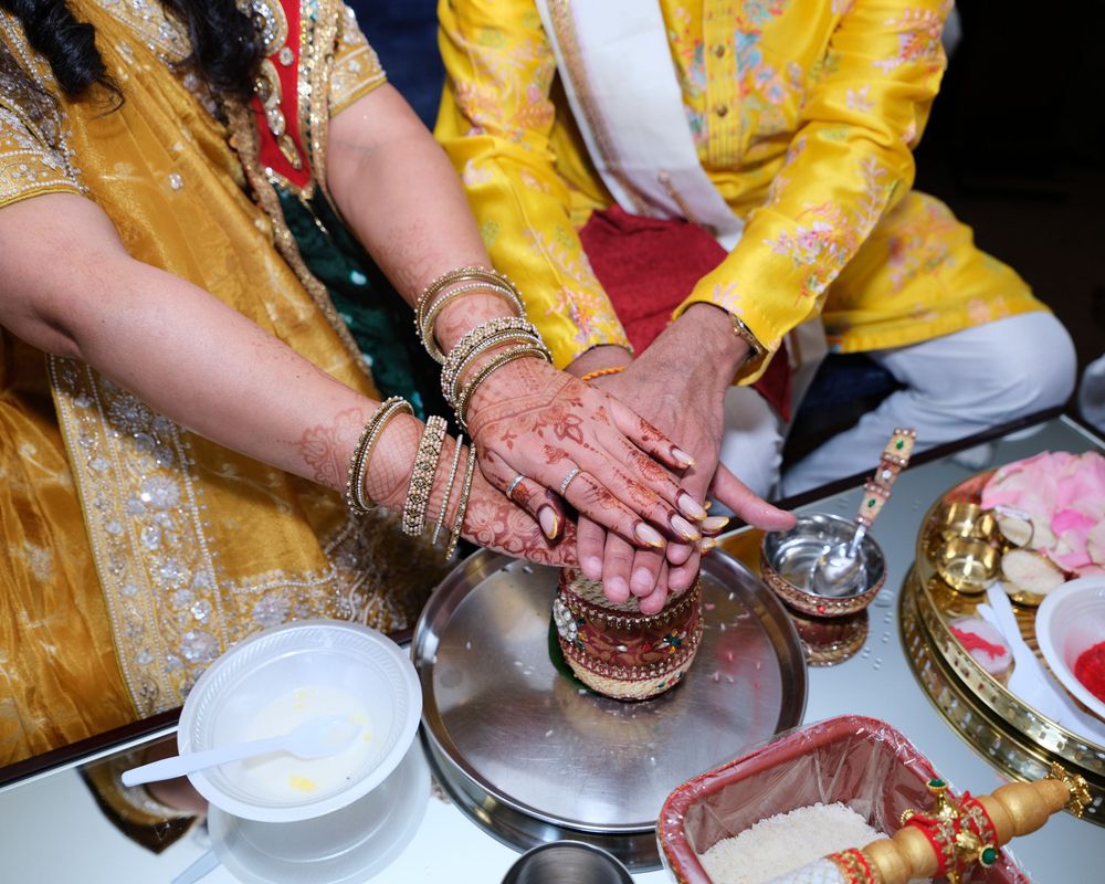 Hands adorned with henna and gold bangles joined together during a traditional Indian wedding ceremony ritual.
