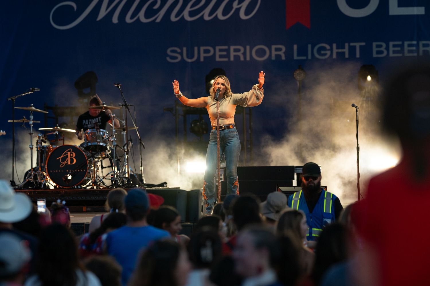 Female singer performs energetically on stage at a Michelob Ultra Superior Light Beer outdoor concert event.