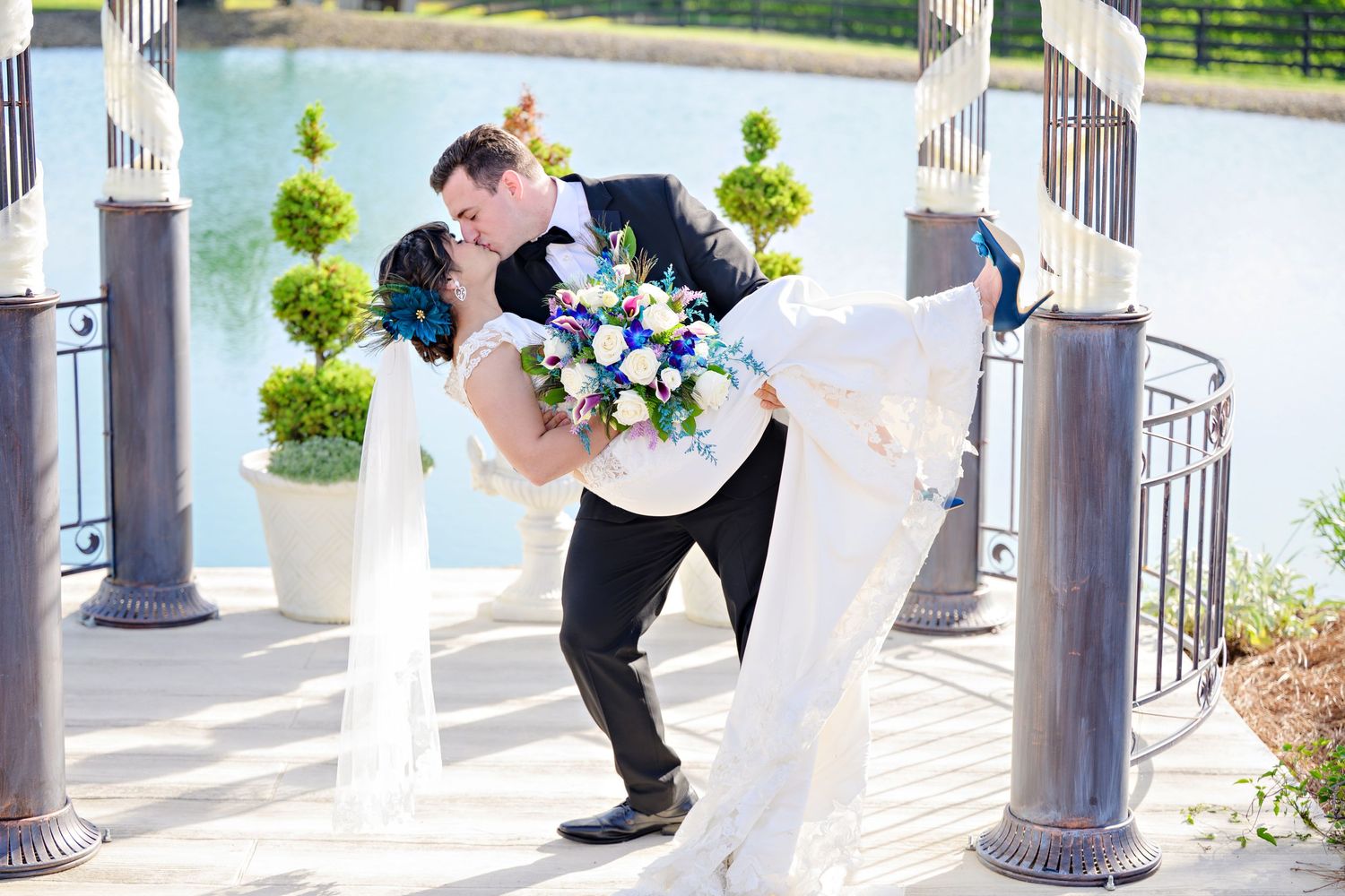 Groom dipping a bride who is wearing a long white wedding gown and blue heels after their wedding at Peacock Ridge in North Lawrence Ohio