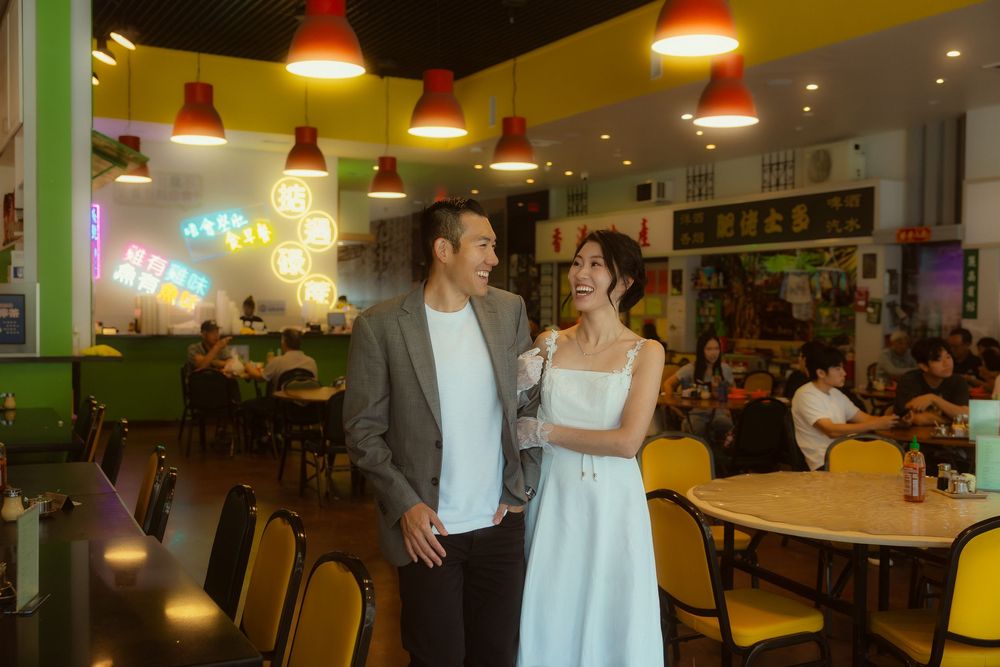Couple smiling together in a vibrant restaurant with yellow chairs, red pendant lights, and colorful decor.