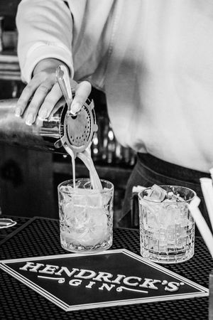 Bartender pouring a cocktail through a strainer into a crystal glass at a Hendrick's Gin branded bar.