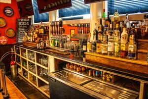 Well-stocked bar interior with rows of liquor bottles, draft taps, and shelves in a cozy Italian restaurant setting.