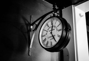 Antique double-sided Victoria Station London wall clock mounted on ornate bracket in black and white.