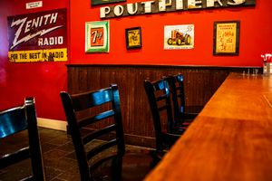 Vintage restaurant interior with red walls, retro signs including Zenith Radio, and dark wood bar seating.