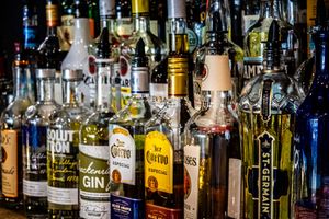 Assorted liquor bottles including gin, tequila, and St. Germain displayed on a bar shelf.