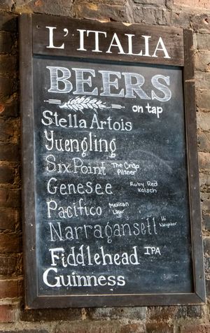 Chalkboard beer menu at L'Italia restaurant listing Stella Artois, Yuengling, Six Point, Genesee, Pacifico, Narragansett, Fiddlehead IPA, Gu