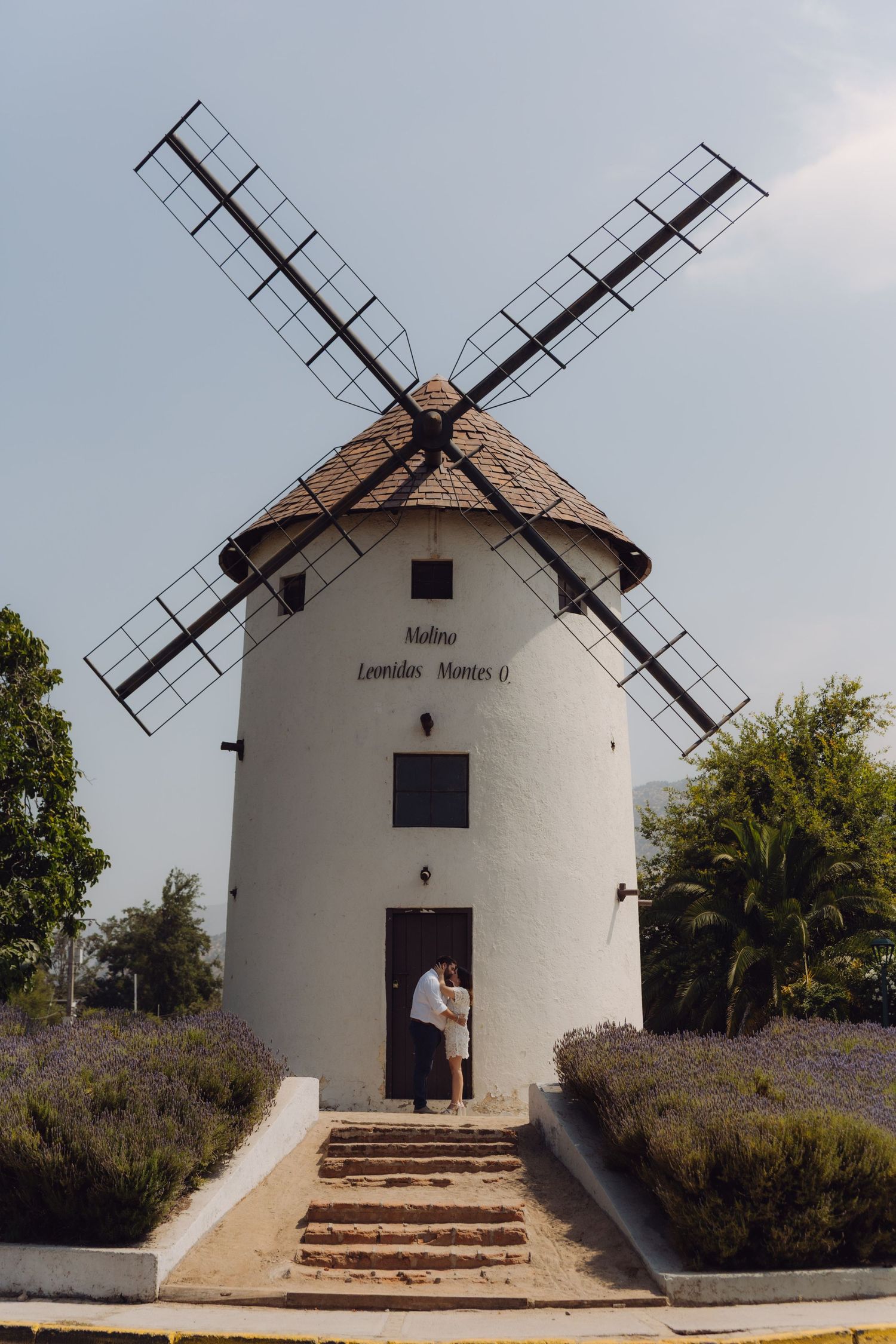 Couple standing together at the entrance of a white windmill named Molino Leonidas Montes.