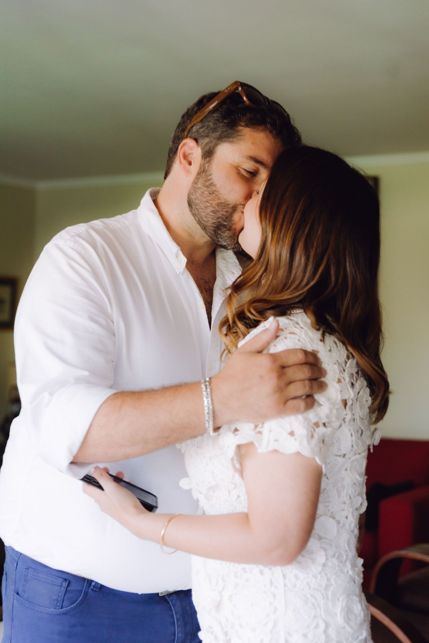 A couple shares a romantic kiss indoors during what appears to be a special occasion.